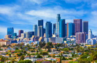 Urban sprawl fills the foreground leading back to the skyscrapers of Los Angeles skyline with cloudscape behind, California