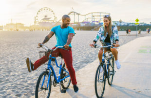 couple having fun riding bikes together at santa monica california near sunset